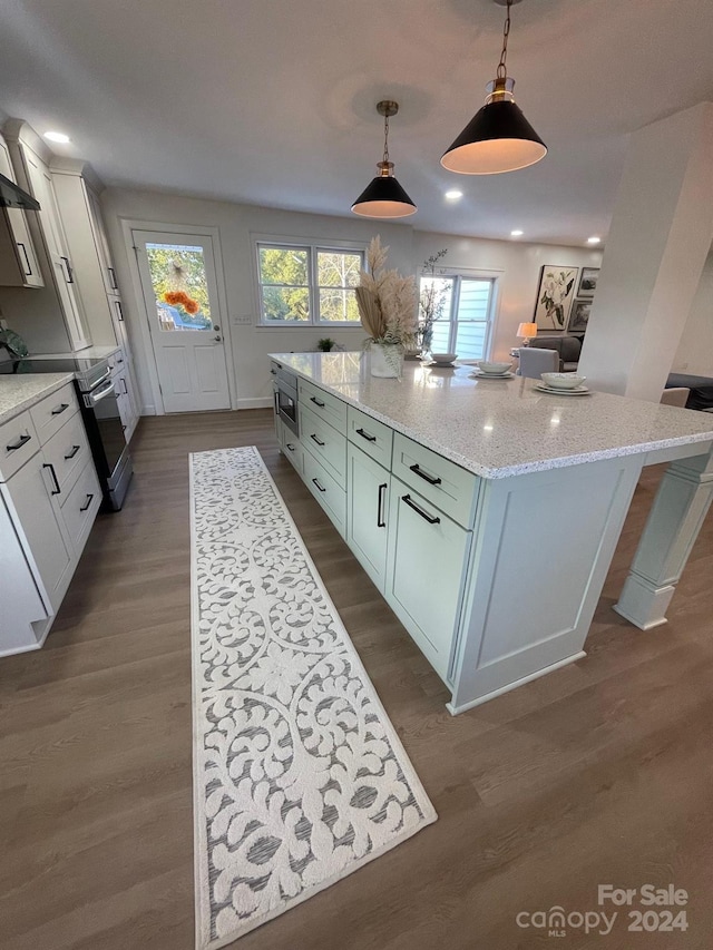 kitchen featuring white cabinets, hanging light fixtures, a kitchen island, stainless steel range oven, and dark hardwood / wood-style flooring