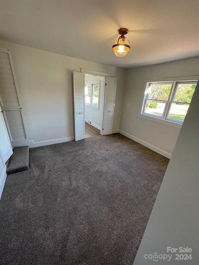 unfurnished bedroom featuring multiple windows and dark carpet