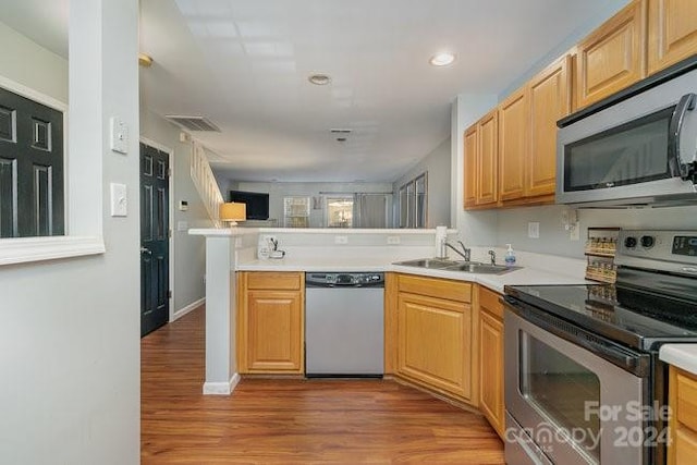 kitchen featuring kitchen peninsula, sink, stainless steel appliances, and light wood-type flooring