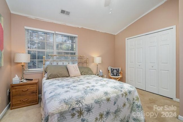 bedroom with ceiling fan, crown molding, light colored carpet, a closet, and vaulted ceiling