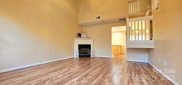 unfurnished living room featuring a towering ceiling and hardwood / wood-style floors