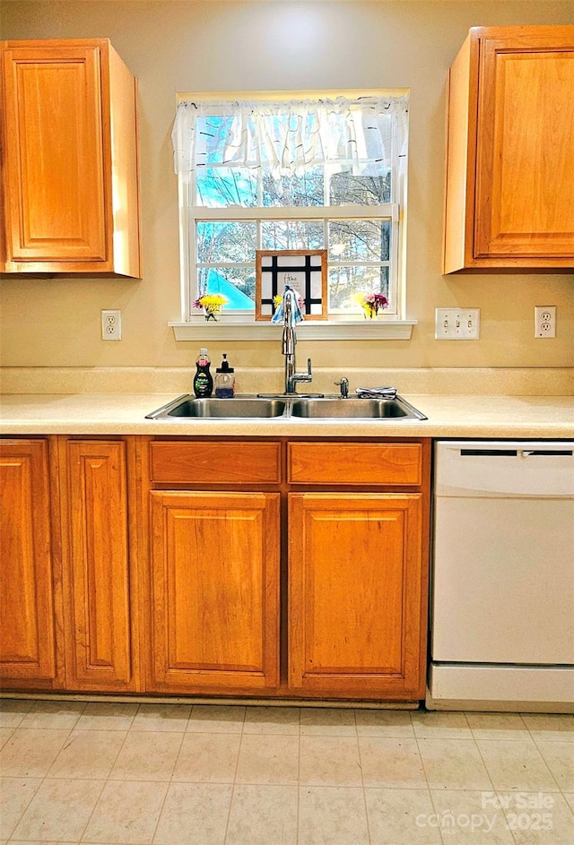 kitchen featuring white dishwasher, sink, and light tile patterned floors