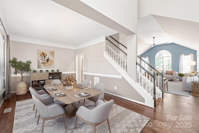 dining room with ceiling fan, crown molding, dark wood-type flooring, and vaulted ceiling