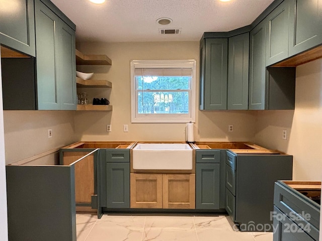 kitchen featuring sink, green cabinetry, and a textured ceiling