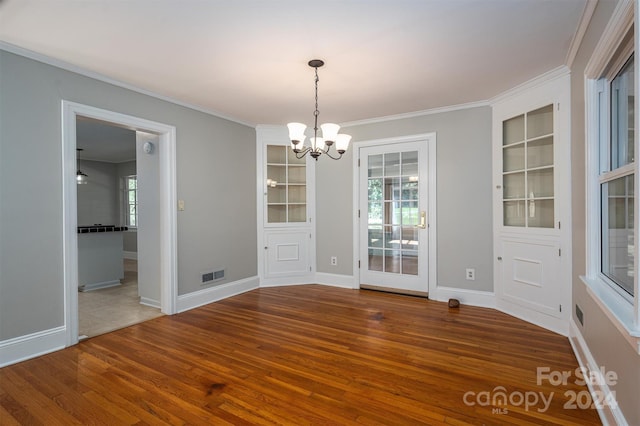 unfurnished dining area with wood-type flooring, a notable chandelier, and ornamental molding