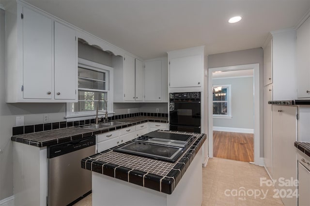 kitchen featuring white cabinets, sink, appliances with stainless steel finishes, tile countertops, and a center island