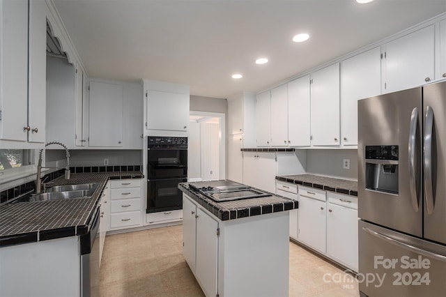 kitchen featuring sink, white cabinetry, stainless steel appliances, tile counters, and a center island