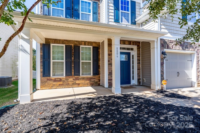 entrance to property with a porch, central AC, and a garage