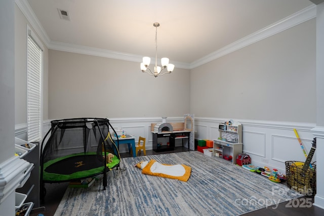 playroom with ornamental molding and a chandelier