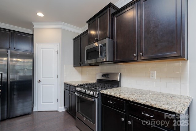 kitchen featuring light stone countertops, stainless steel appliances, dark hardwood / wood-style floors, backsplash, and ornamental molding