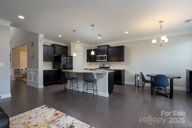 kitchen with pendant lighting, sink, stainless steel appliances, and an island with sink