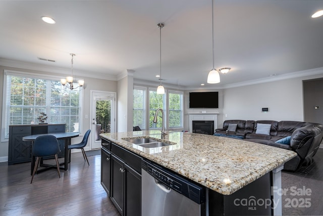 kitchen featuring a center island with sink, sink, hanging light fixtures, stainless steel dishwasher, and plenty of natural light