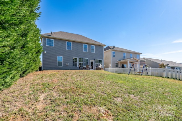 rear view of house with a lawn, central AC, and a playground