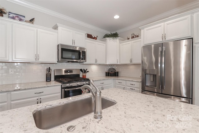 kitchen featuring appliances with stainless steel finishes, light stone counters, ornamental molding, and white cabinets