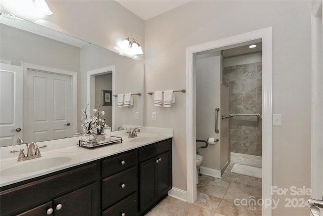 bathroom with a tile shower, vanity, tile patterned flooring, and toilet