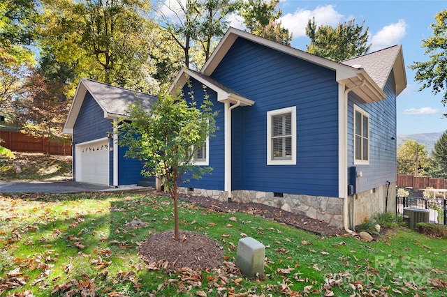 view of front of house with central AC unit, a garage, and a front lawn