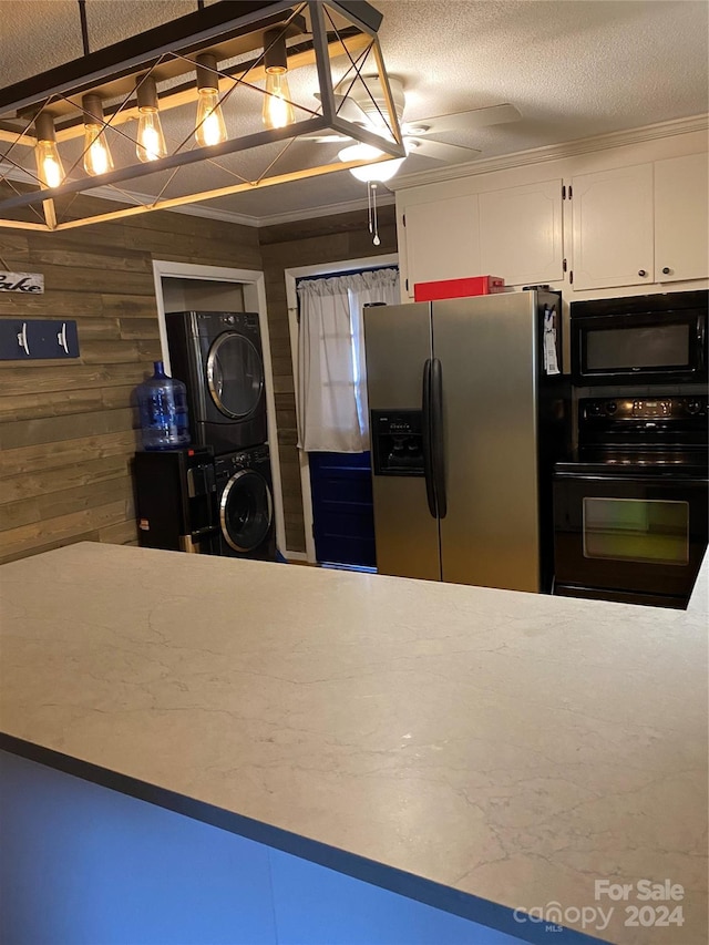 kitchen with white cabinetry, stacked washing maching and dryer, black appliances, crown molding, and wooden walls