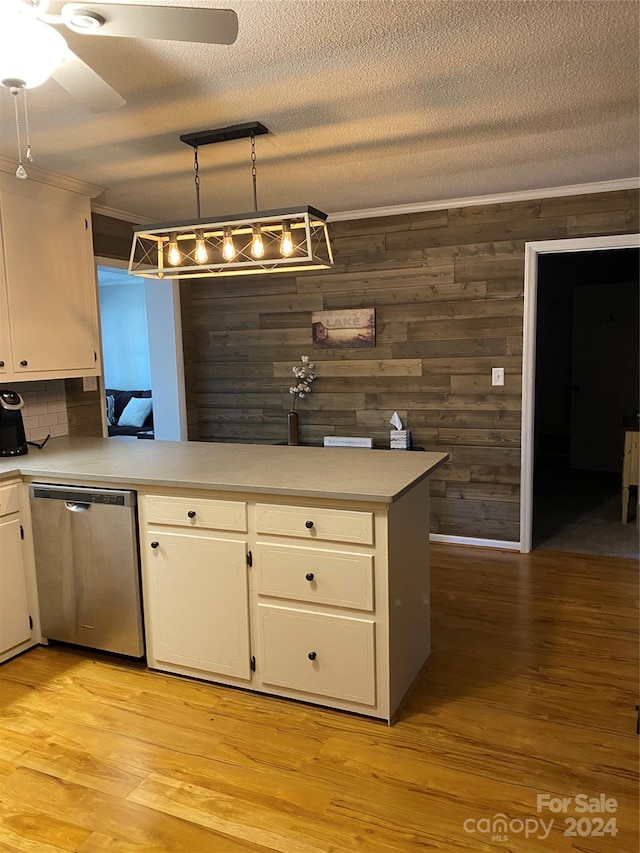 kitchen with tasteful backsplash, hanging light fixtures, light wood-type flooring, dishwasher, and wooden walls