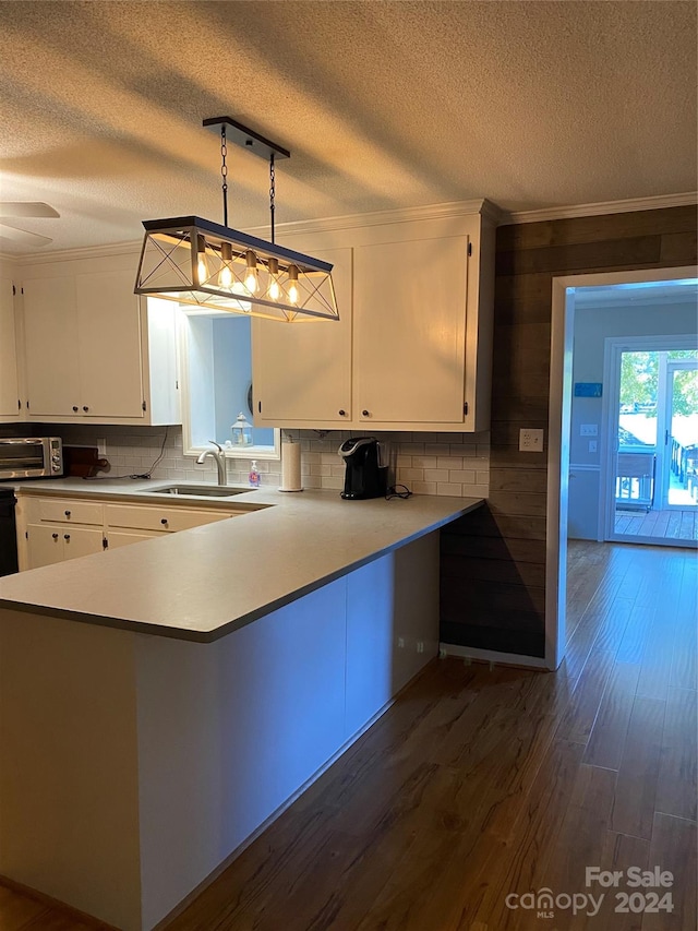 kitchen featuring kitchen peninsula, sink, dark wood-type flooring, and pendant lighting