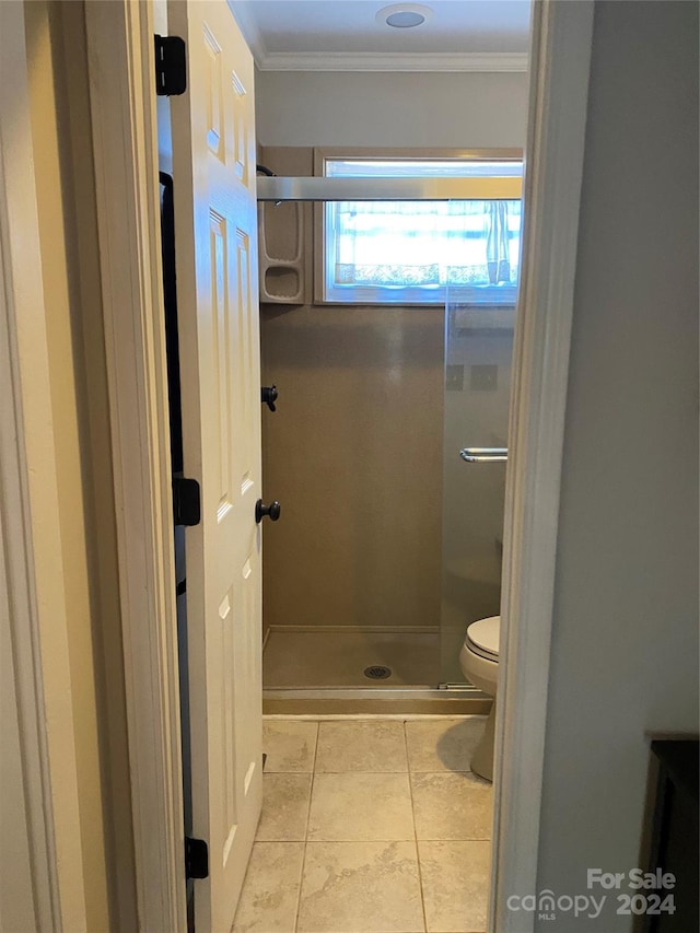 bathroom featuring toilet, crown molding, a shower, and tile patterned flooring