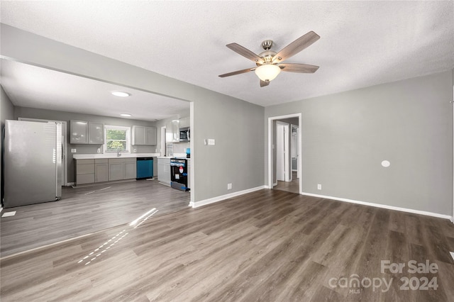 unfurnished living room featuring ceiling fan, wood-type flooring, and a textured ceiling