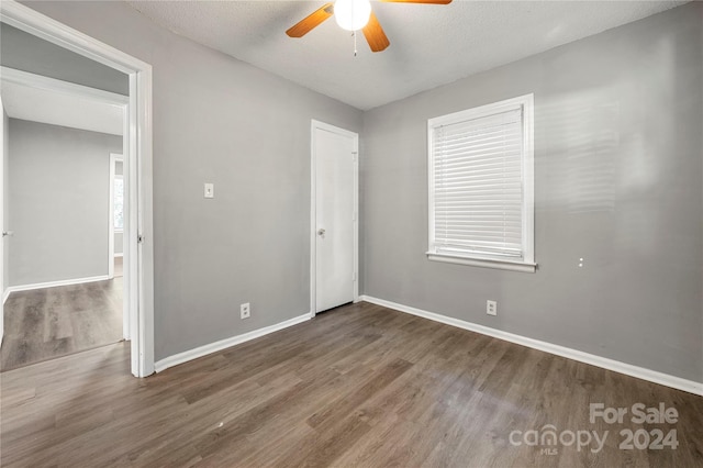 unfurnished bedroom featuring ceiling fan, a textured ceiling, and dark hardwood / wood-style floors