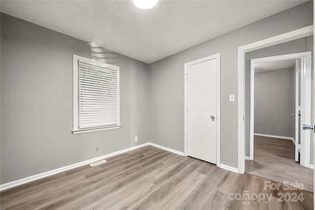 unfurnished bedroom with a textured ceiling and light hardwood / wood-style flooring