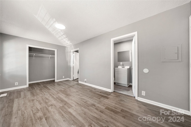 unfurnished bedroom with hardwood / wood-style floors, a closet, sink, connected bathroom, and a textured ceiling