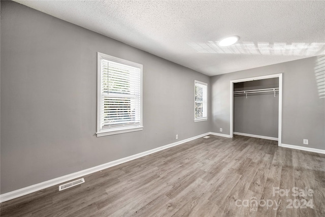 unfurnished bedroom with a closet, hardwood / wood-style floors, and a textured ceiling