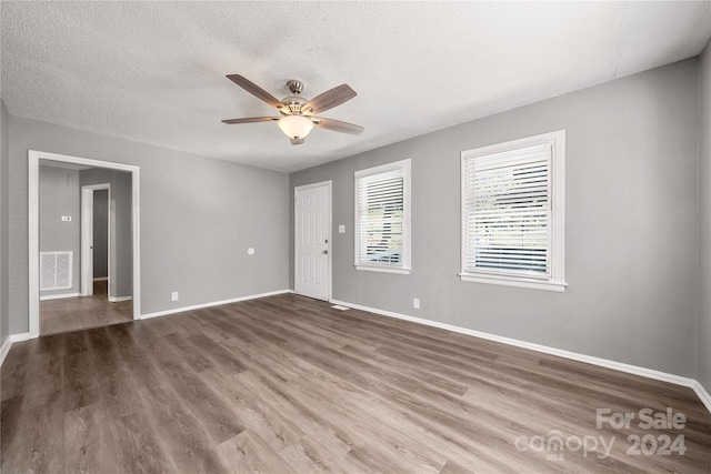 empty room with ceiling fan, dark wood-type flooring, and a textured ceiling