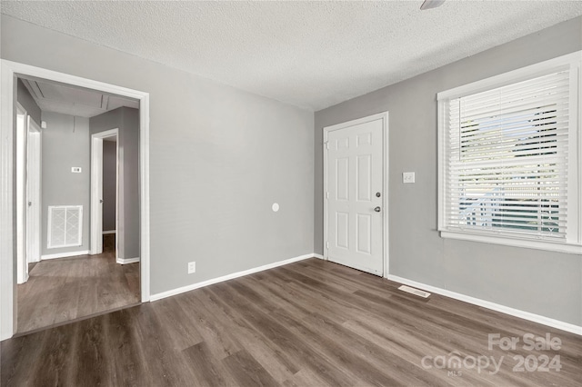 empty room featuring a textured ceiling and dark hardwood / wood-style floors