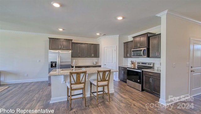 kitchen with an island with sink, light stone countertops, dark hardwood / wood-style floors, stainless steel appliances, and crown molding