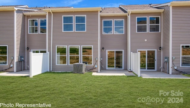 rear view of property featuring central air condition unit and a lawn