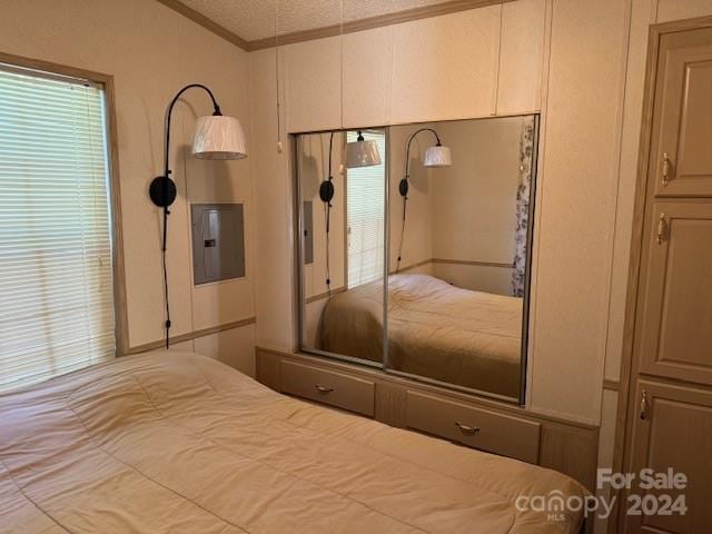 bedroom with electric panel, ornamental molding, and a textured ceiling