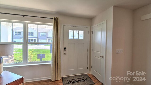 doorway with baseboards, dark wood-type flooring, and visible vents