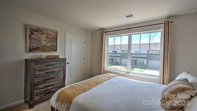 bedroom with baseboards, visible vents, and light carpet