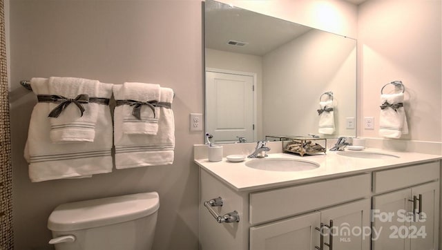 bathroom with visible vents, a sink, double vanity, and toilet
