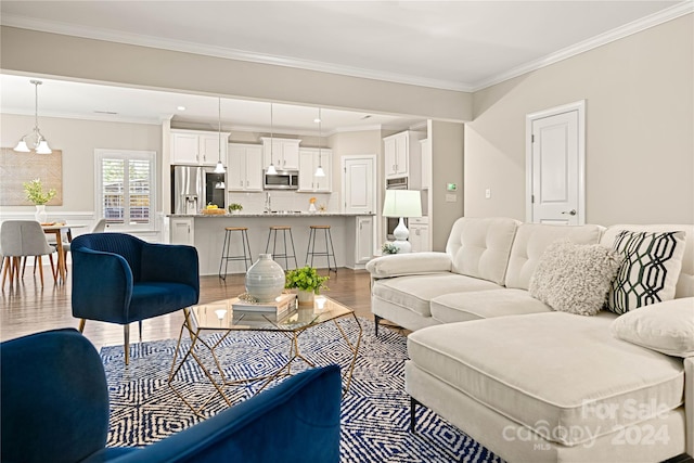 living room with hardwood / wood-style flooring, crown molding, and a notable chandelier