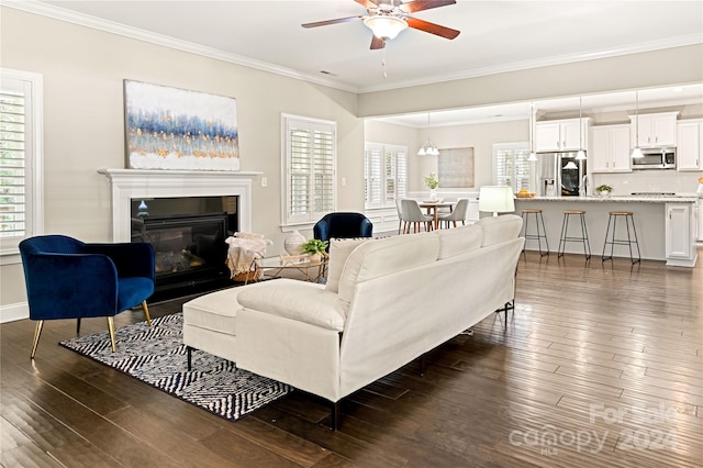 living room featuring dark wood-type flooring, ornamental molding, and a healthy amount of sunlight