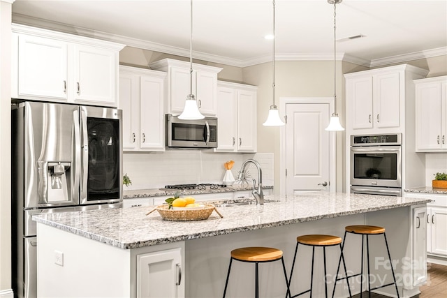 kitchen featuring sink, appliances with stainless steel finishes, a kitchen island with sink, white cabinets, and pendant lighting