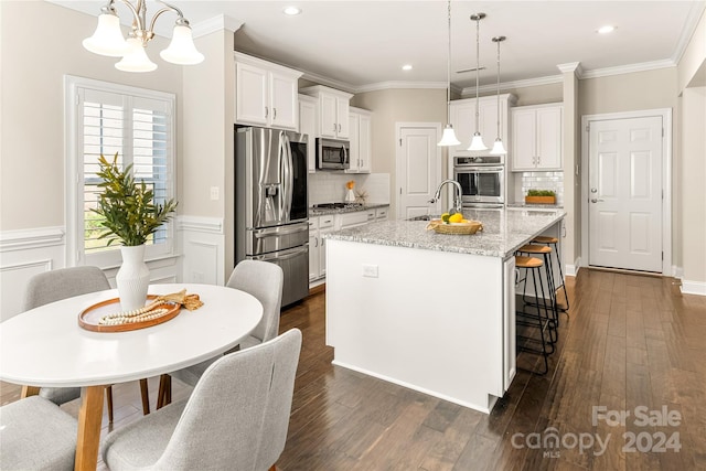 kitchen with white cabinets, dark hardwood / wood-style floors, a kitchen island with sink, and appliances with stainless steel finishes