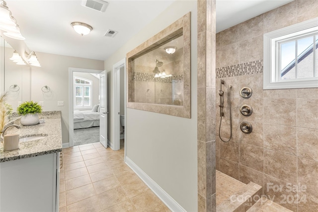 bathroom with tile patterned flooring, plenty of natural light, vanity, and a tile shower