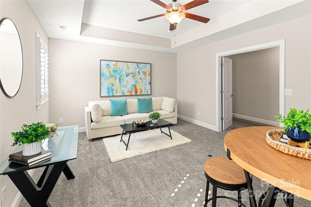 living room featuring carpet flooring, ceiling fan, and a tray ceiling