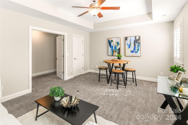 carpeted living room featuring ceiling fan and a raised ceiling