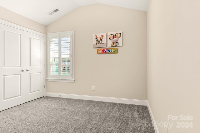 unfurnished bedroom featuring carpet flooring, vaulted ceiling, and a closet