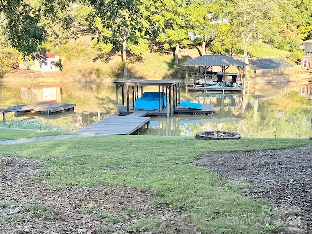 view of dock featuring a water view, an outdoor fire pit, and a yard