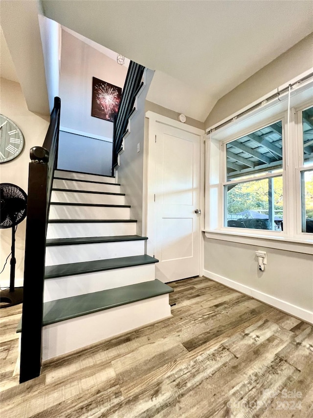 staircase featuring vaulted ceiling and hardwood / wood-style flooring