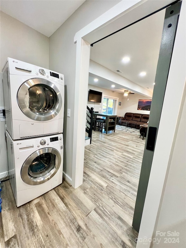 laundry area with stacked washer / drying machine, ceiling fan, and light hardwood / wood-style flooring