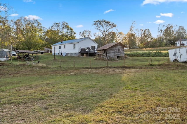 view of yard featuring a rural view, a deck, and a storage unit