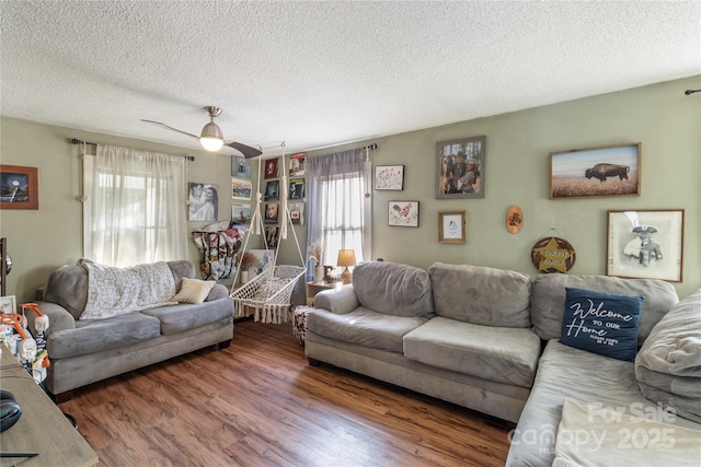 living room with dark wood-type flooring, ceiling fan, a healthy amount of sunlight, and a textured ceiling